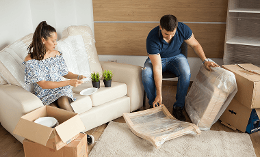 young-couple-moving-new-home-unpacking-carboard-boxes-almost-done-moving 1